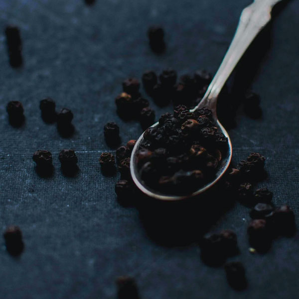 Black pepper with a spoon in dark background